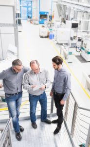 business owners discussing paper on clipboard in factory